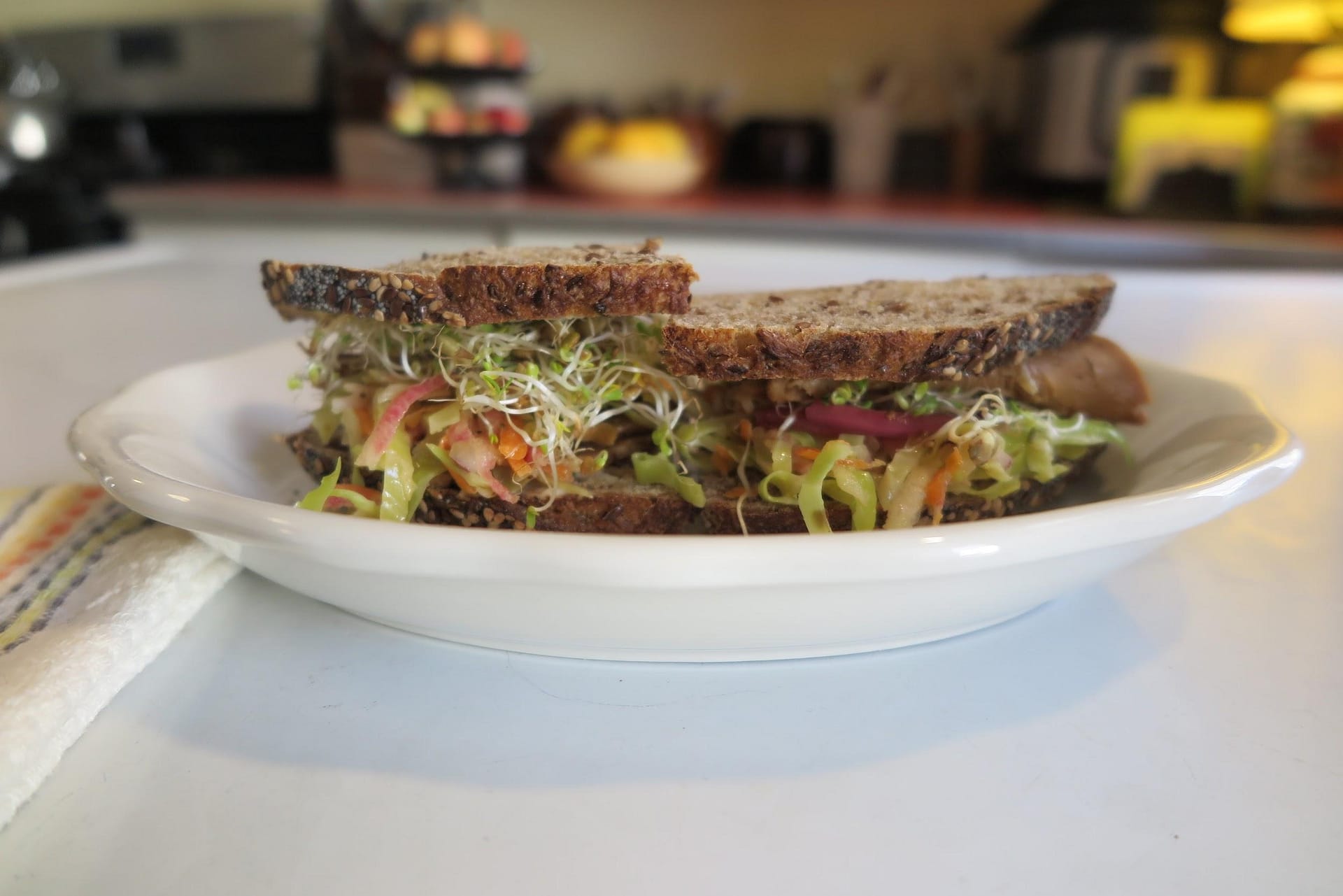 Profile shot of a sandwich with the coleslaw on a white plate.