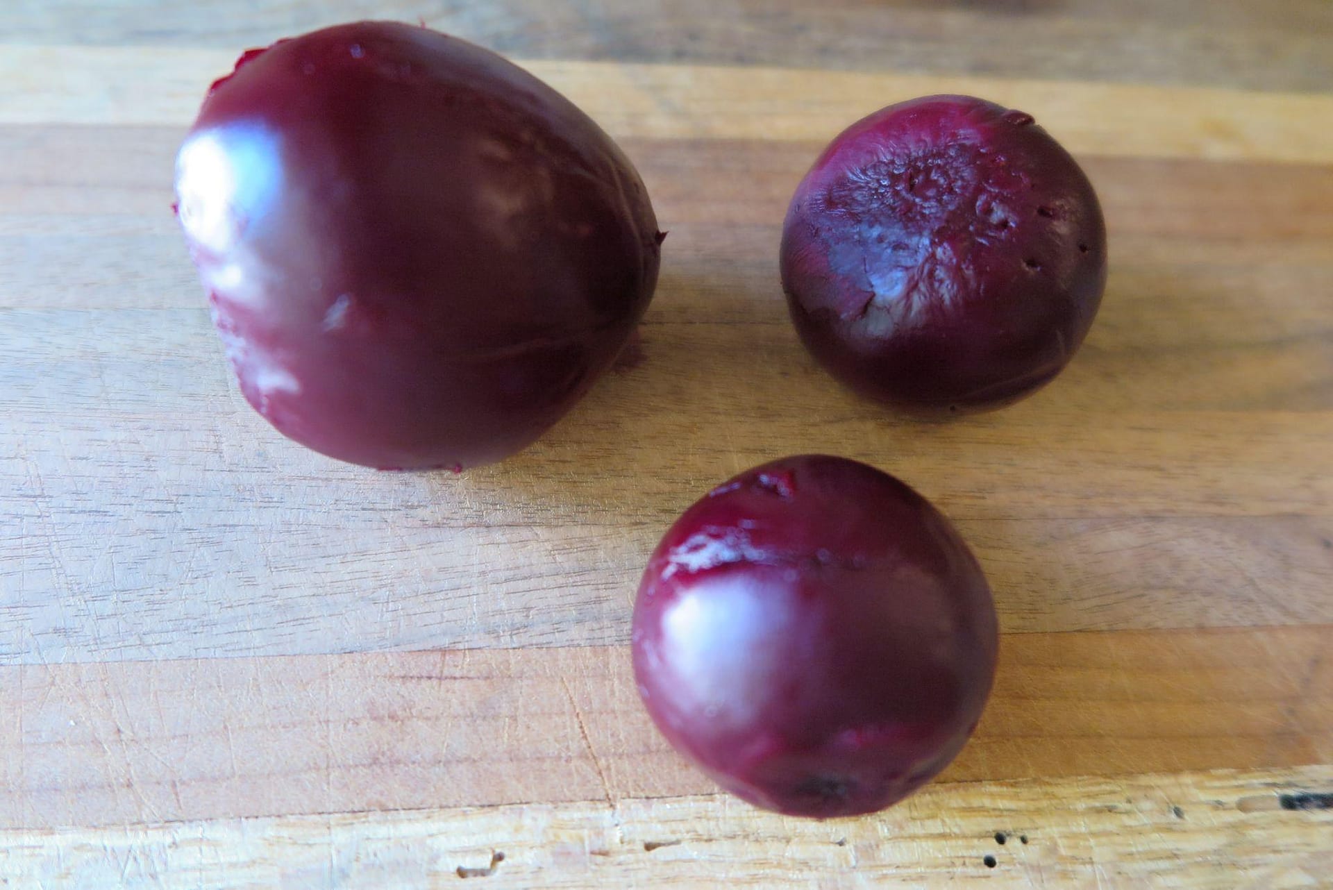 Three beets, cooked and cleaned, on a wood background