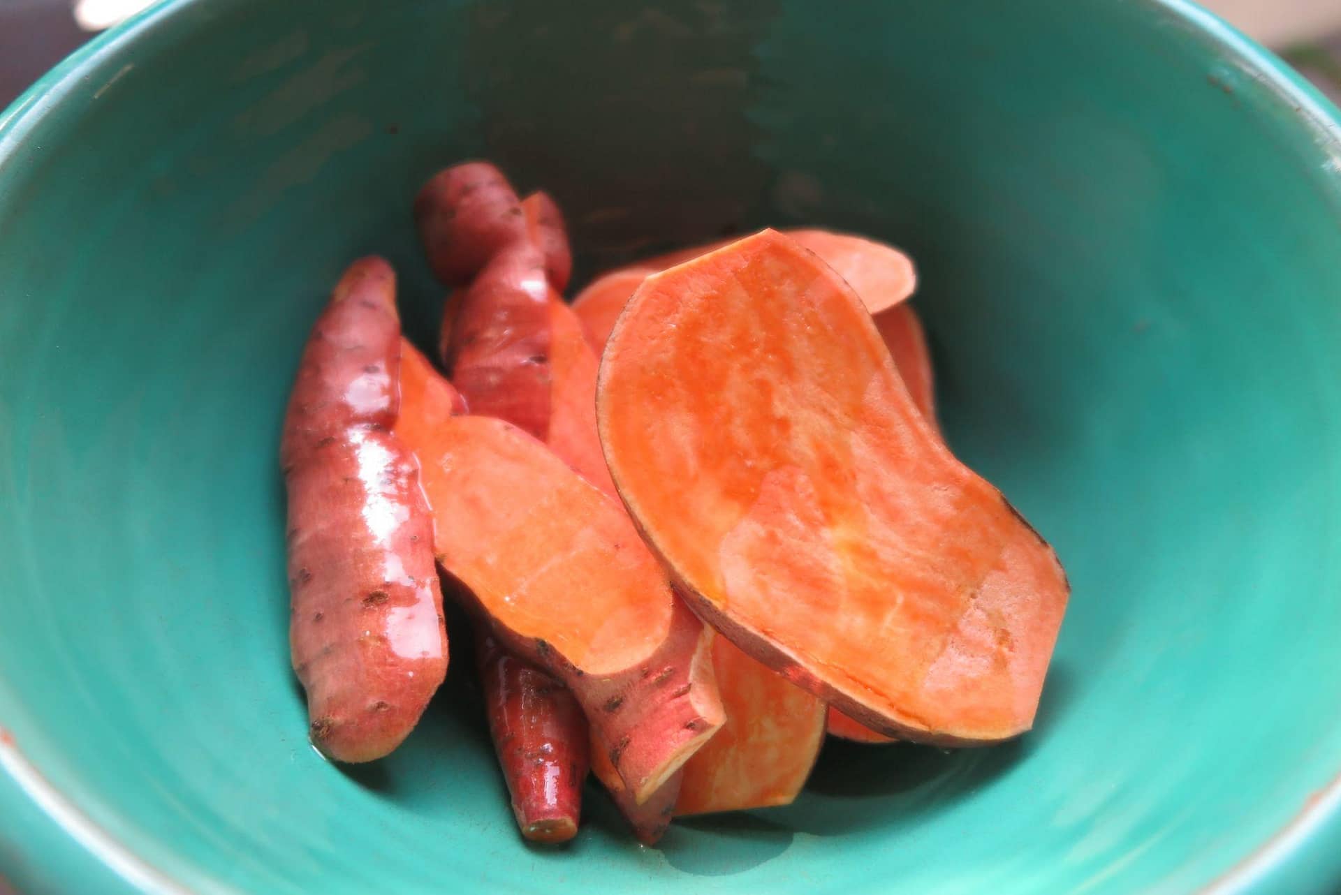 Sliced sweet potatoes in a teal bowl