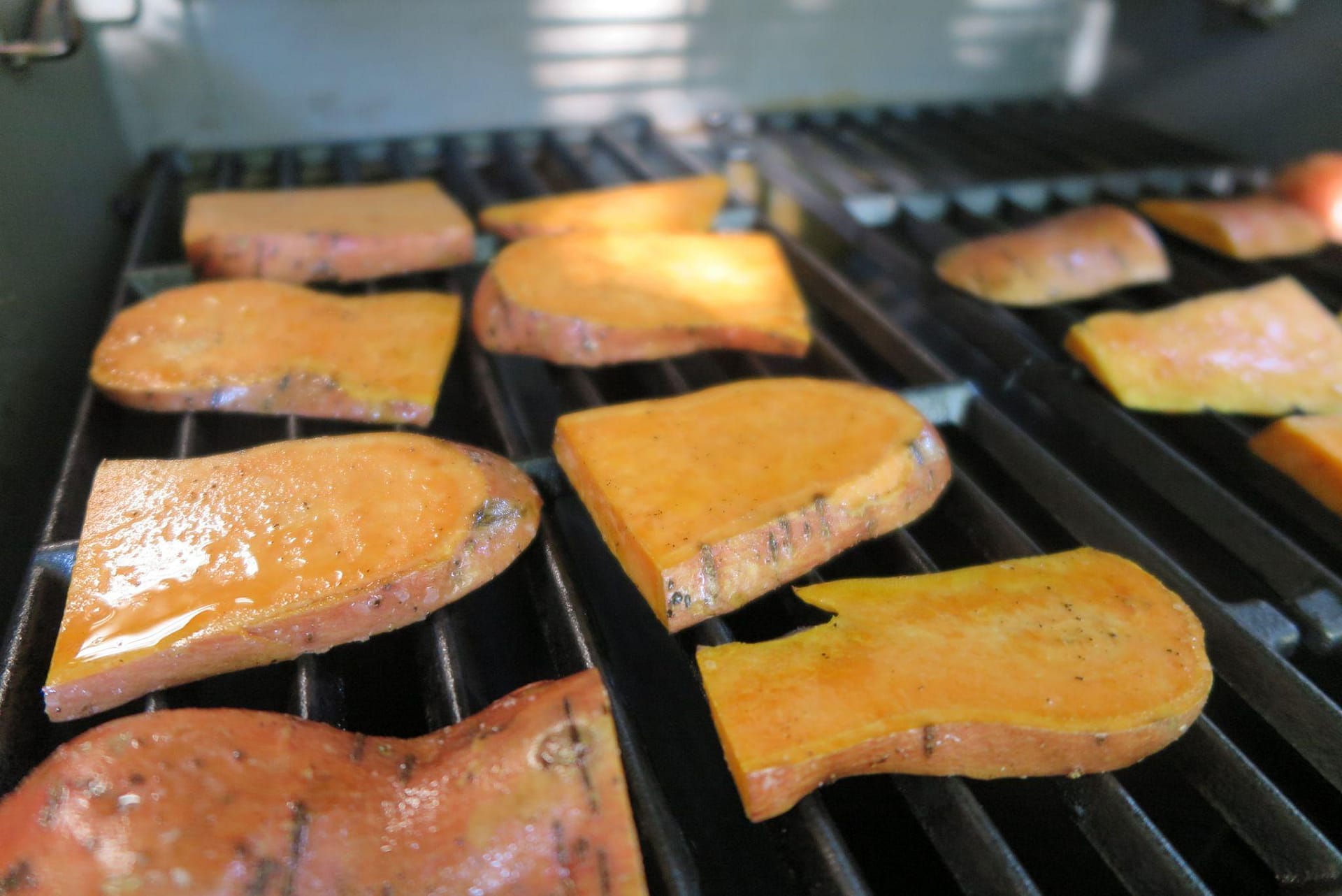 Sweet potatoes lined up on a grill