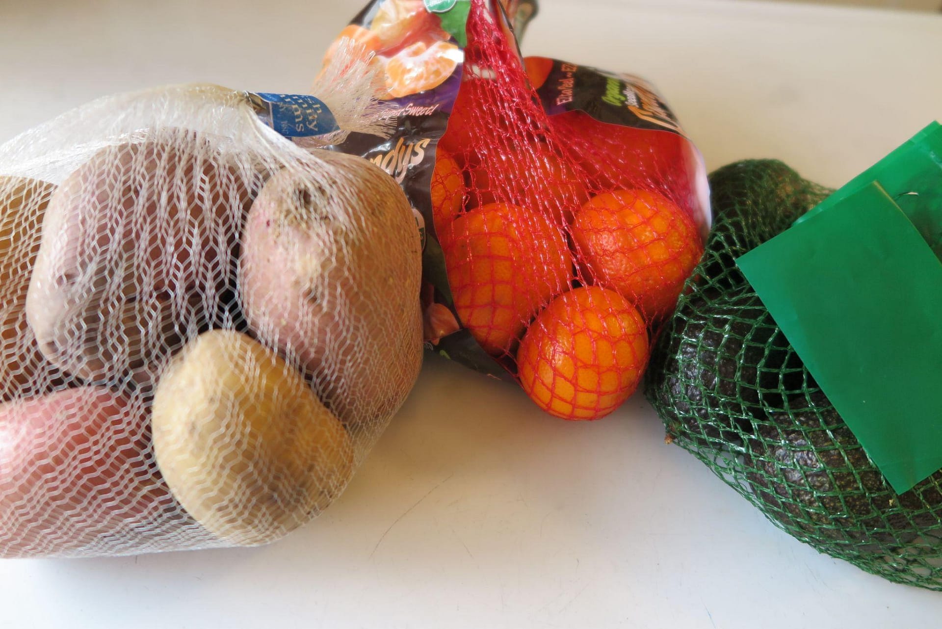 Potatoes, clementines, and avocados in plastic mesh produce bags showing the different types and textures the bags come in