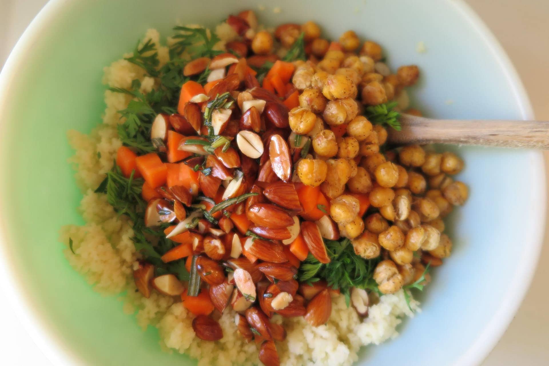 Bowl of salad elements, unmixed. Chickpeas, almonds, and chopped carrots are visible on top