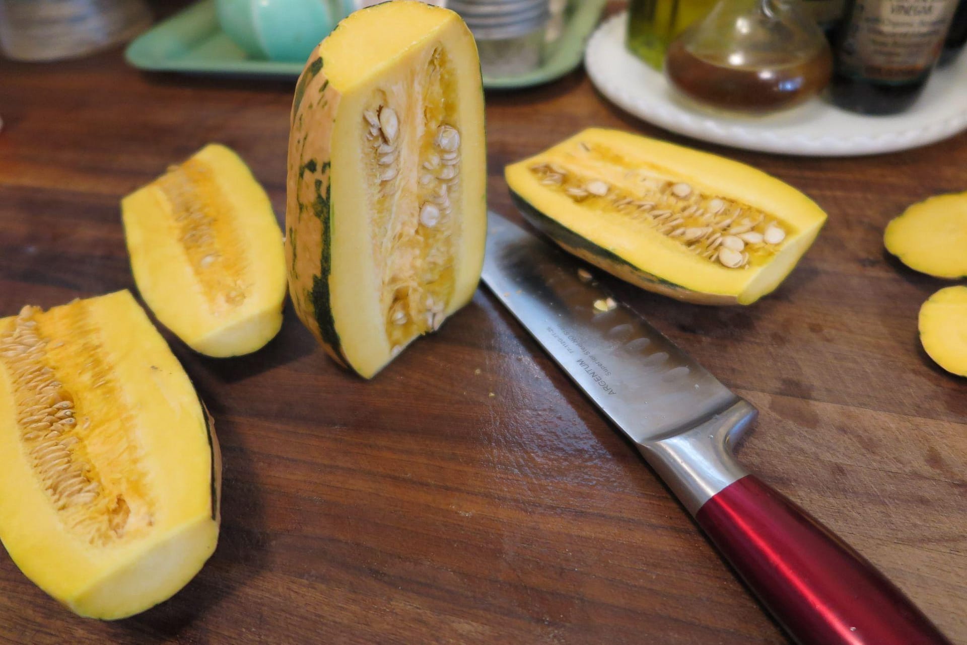 Delicata squash shown slived in half vertically on a wood cutting board