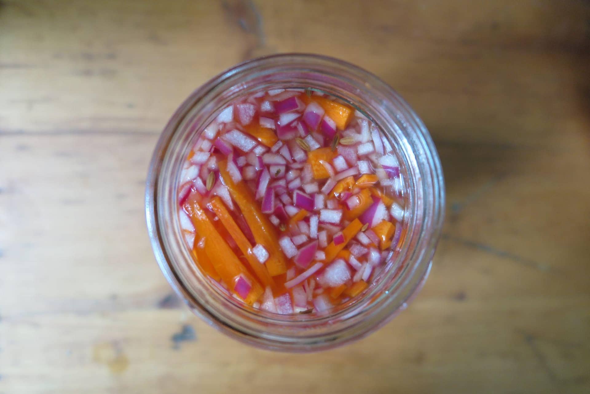 Overhead shot of a canning jar of quick pickled carrots and red onions