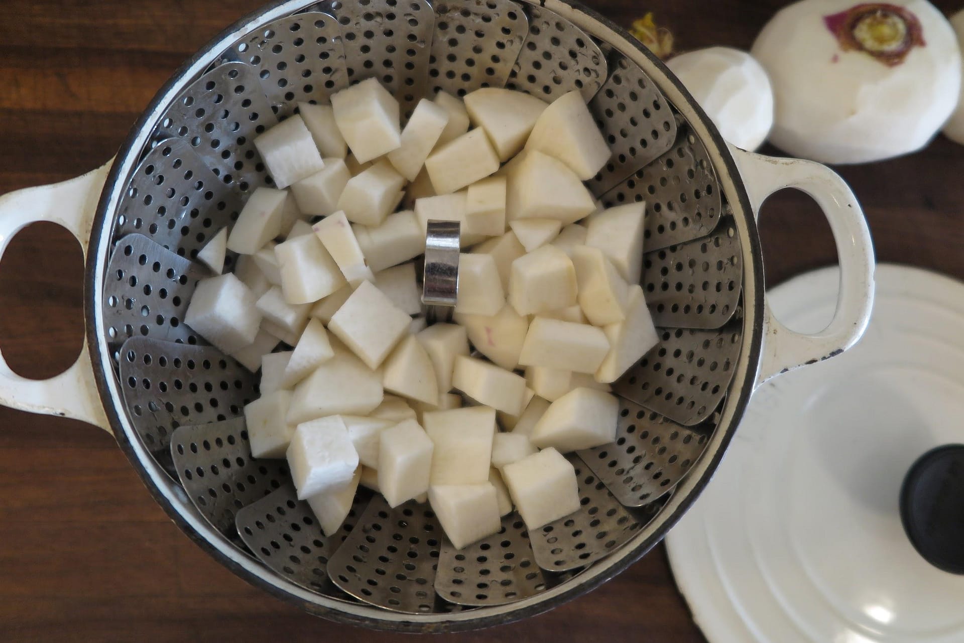 White cubes of rutabagas in a metal steamer basket