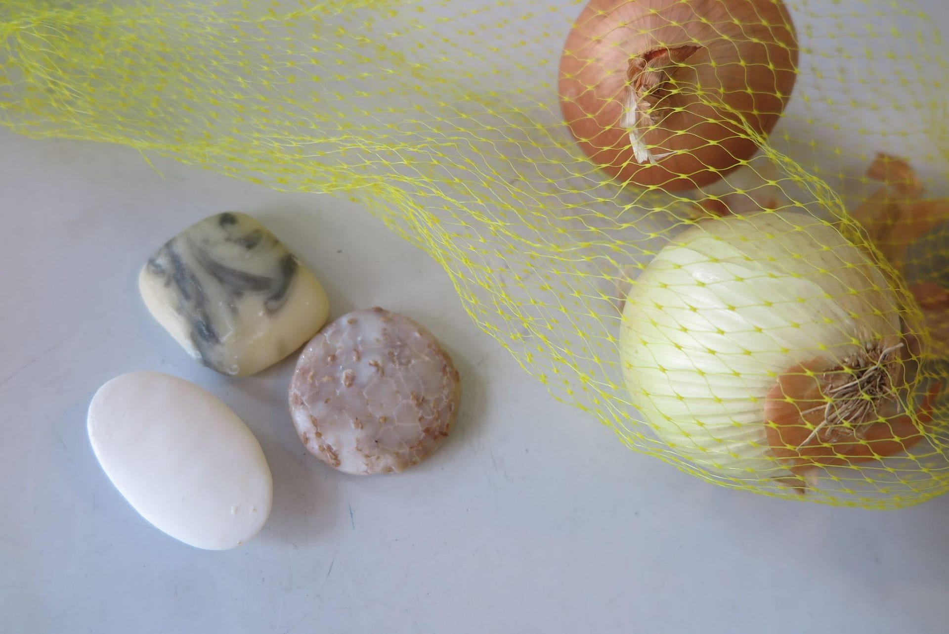 Onions in yellow mesh produce bag next to a few scraps of bar soap